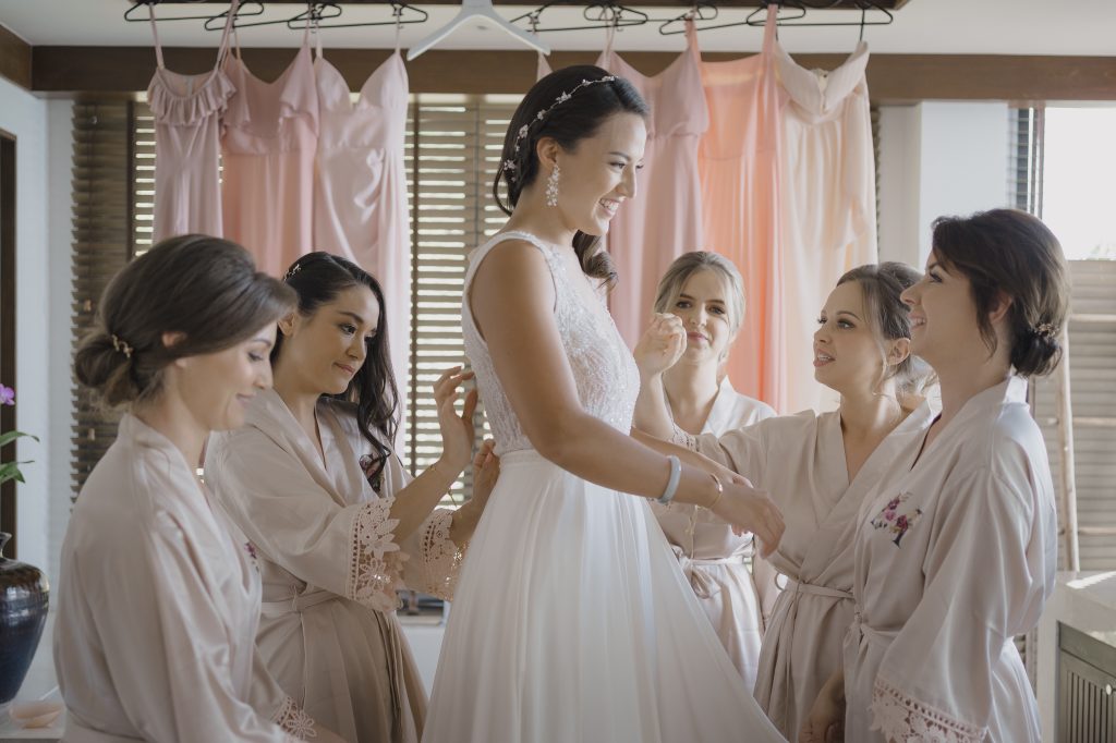 Krabi wedding photographer captures bridesmaids helping bride with dress.