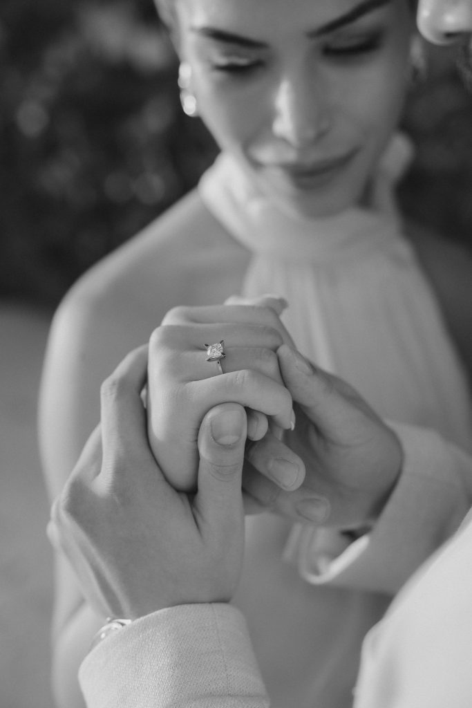 Black and white close-up of a couple’s hands with an engagement ring