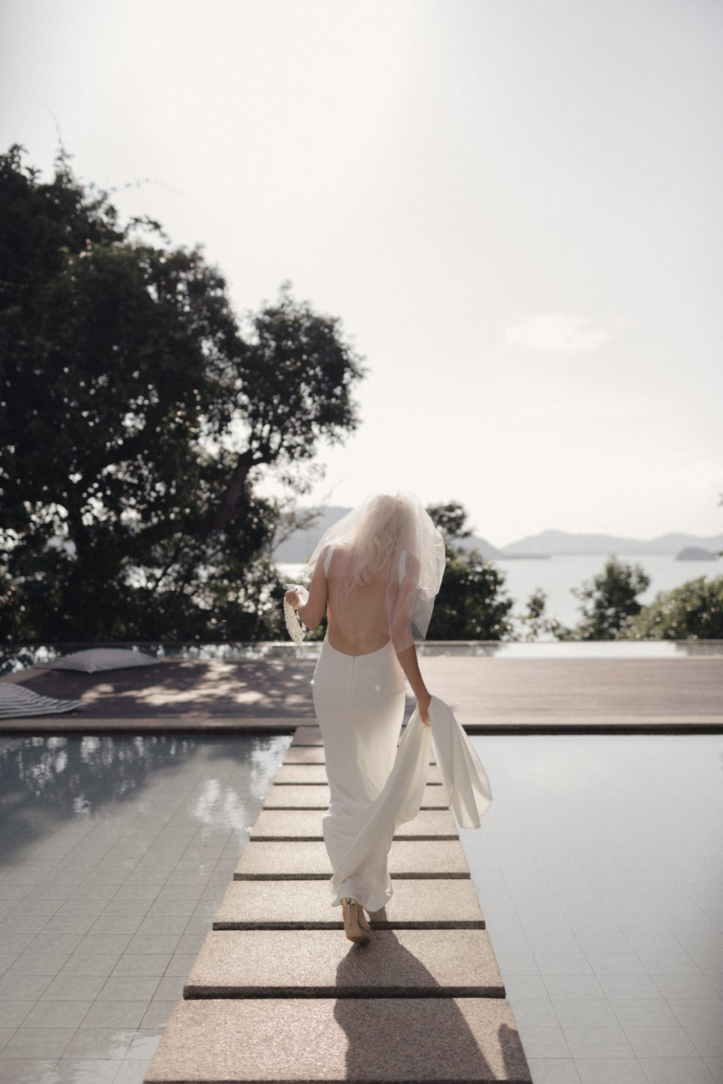 American bride walking across the pool at luxury resort wedding on Koh Samui. Photography by Daniel Baci