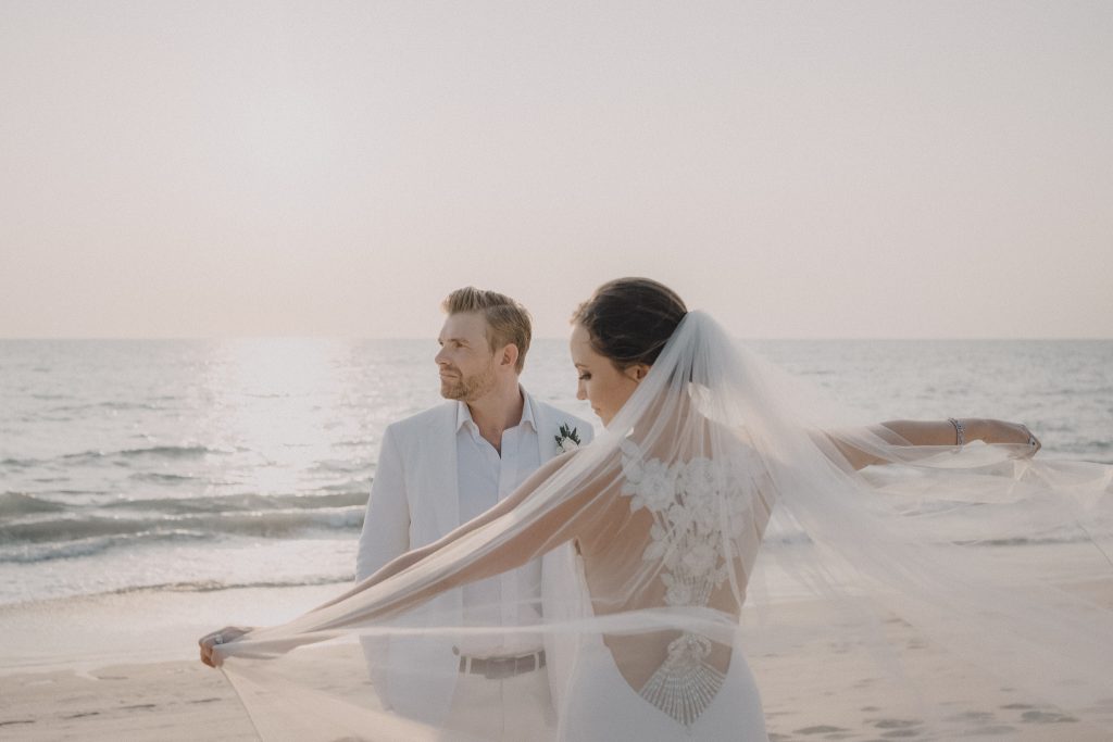 Bride waves her veil in the win during sunset at Jivana Villas in Thailand.
