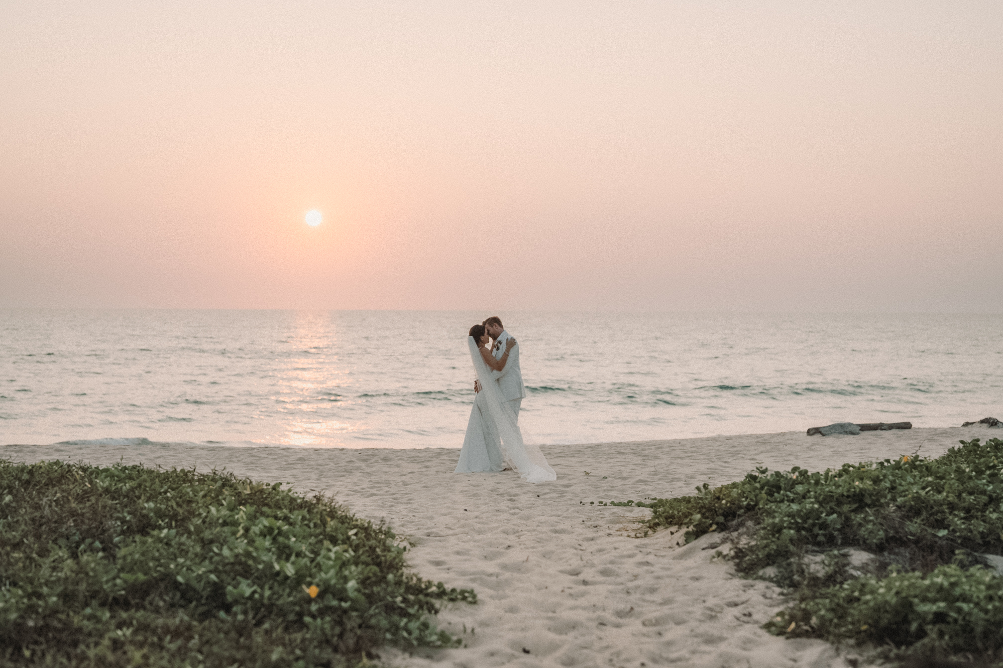 bride and groom kiss during the sunset on the beach in Phuket, Thailand.