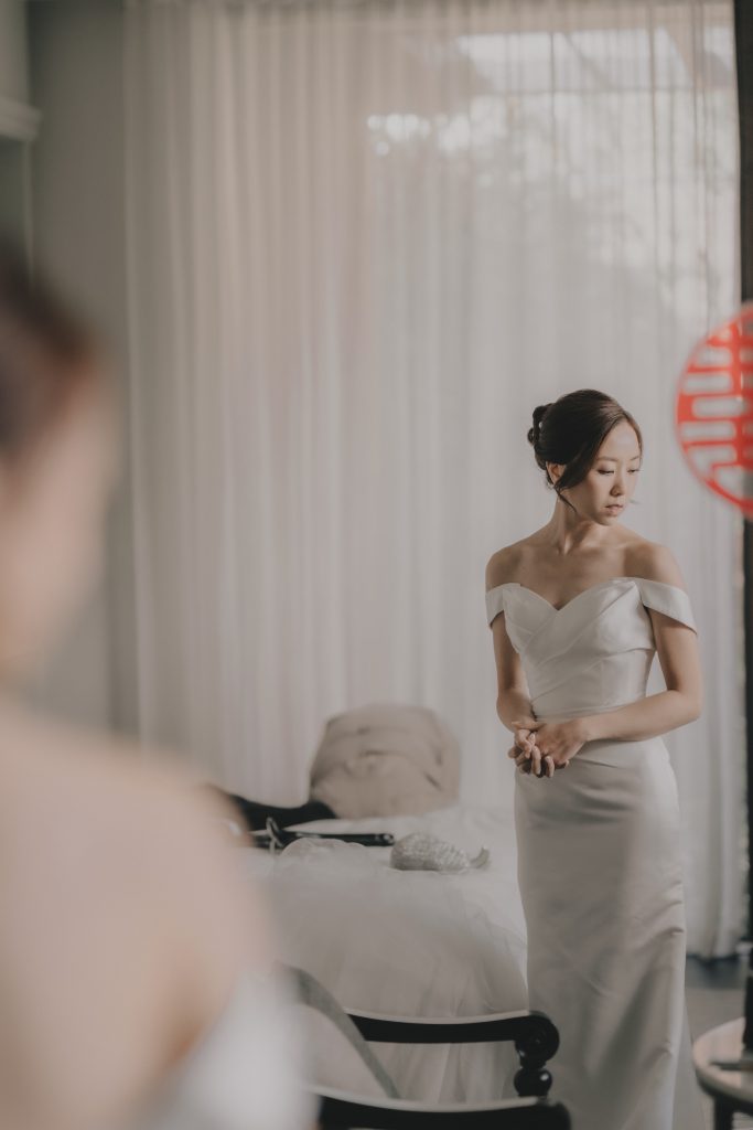 Bride standing in a bright room with a red double happiness decoration