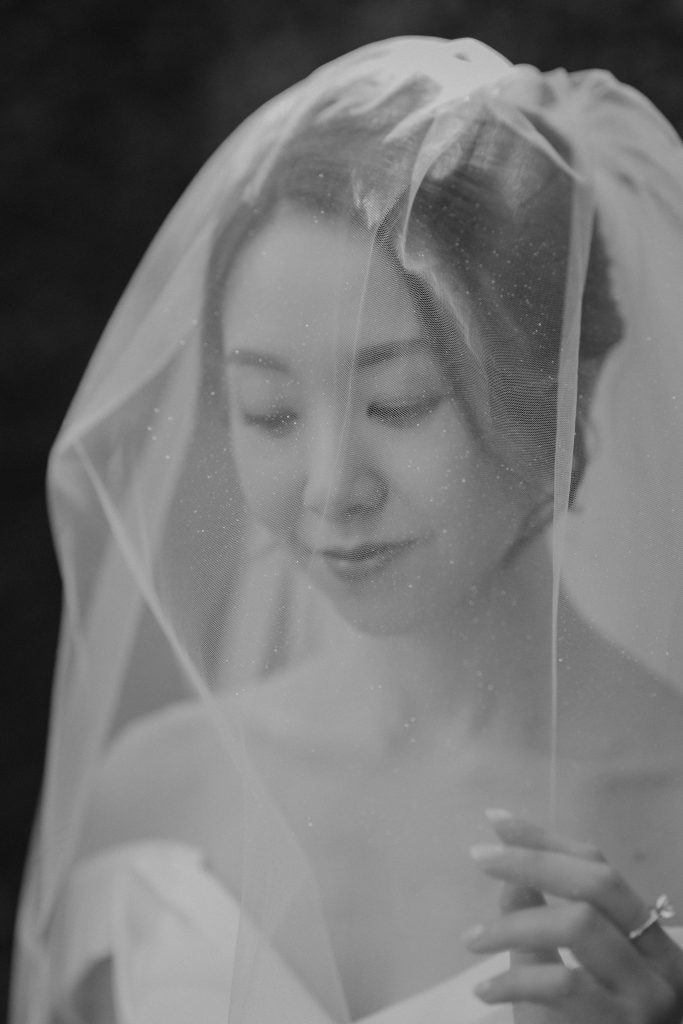 Black and white portrait of a bride looking down through her sheer veil