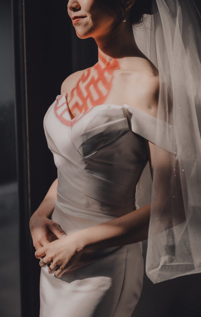 Bride in a veil with a red double happiness symbol across her gown