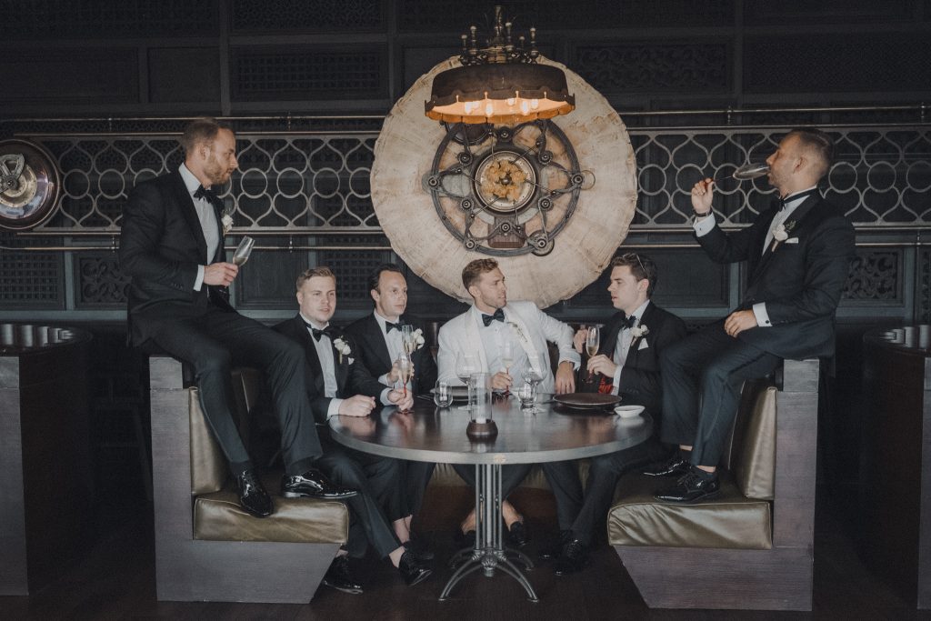 Groomsmen relaxing in a moody lounge before the ceremony
