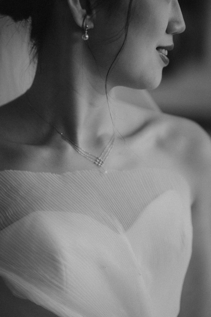 Black and white close-up of a bride’s necklace and sweetheart neckline