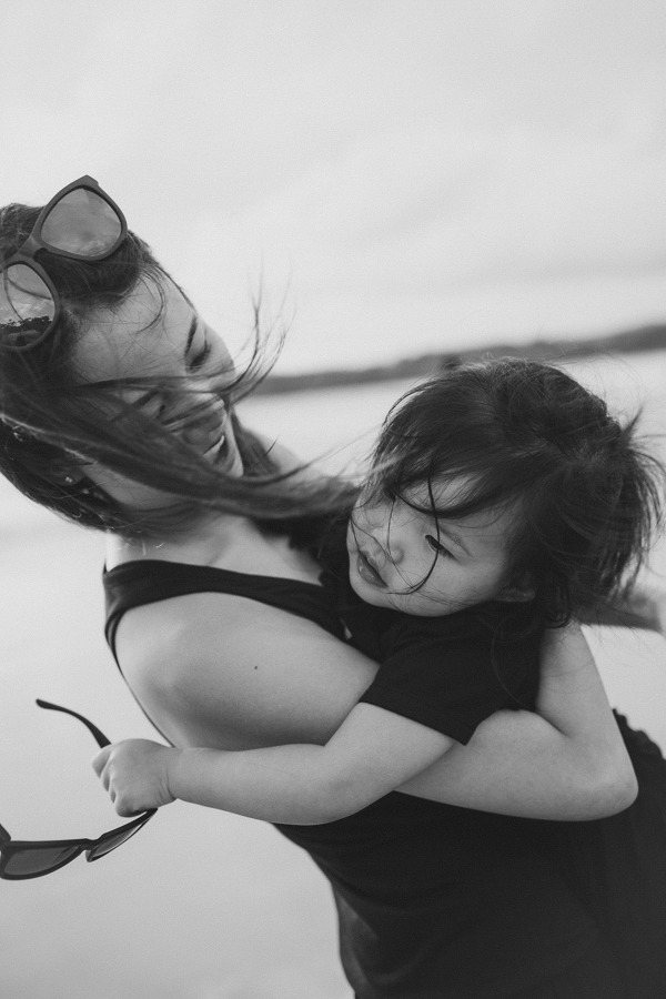 Mother spins daughter playfully on the beach in Thailand.